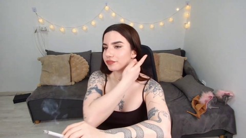 Jeune fille tatouée et sexy s'adonne à une fétichisme de la cigarette